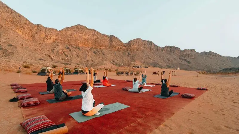 Person practicing yoga in a serene desert wellness setting